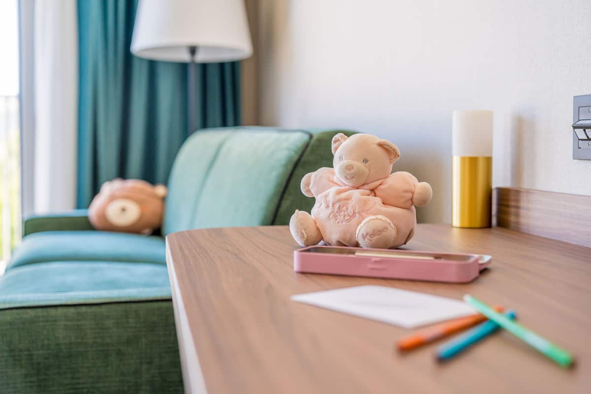 A cozy room with a green sofa, a small teddy bear, a pink phone, and a lamp.