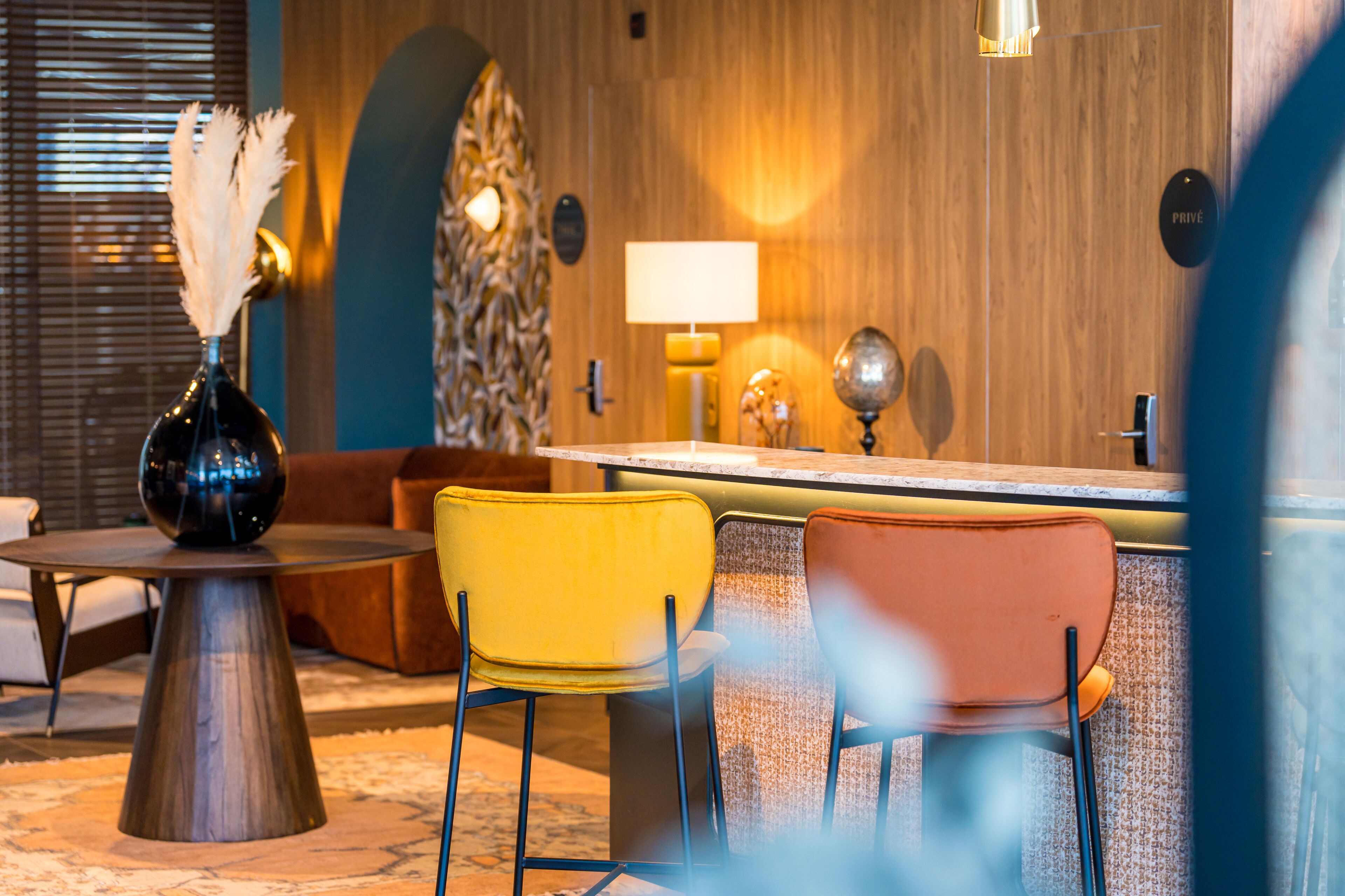 A modern bar area with a wooden wall, a round table, and two chairs.