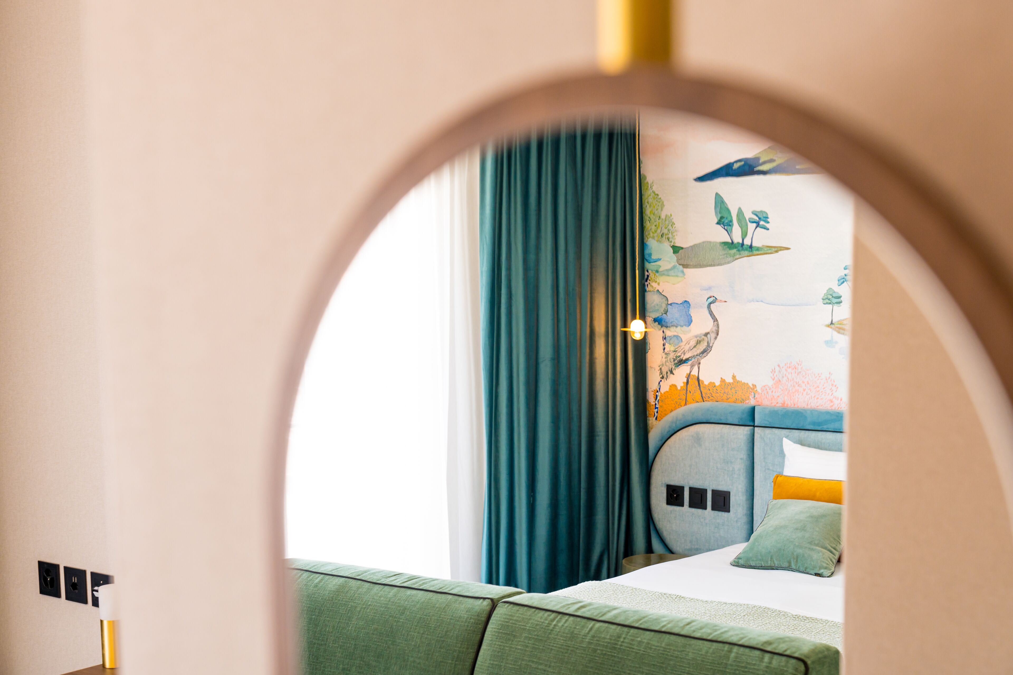 Ein Schlafzimmer mit einem Bett, einem grünen Sofa und einem Wandgemälde.