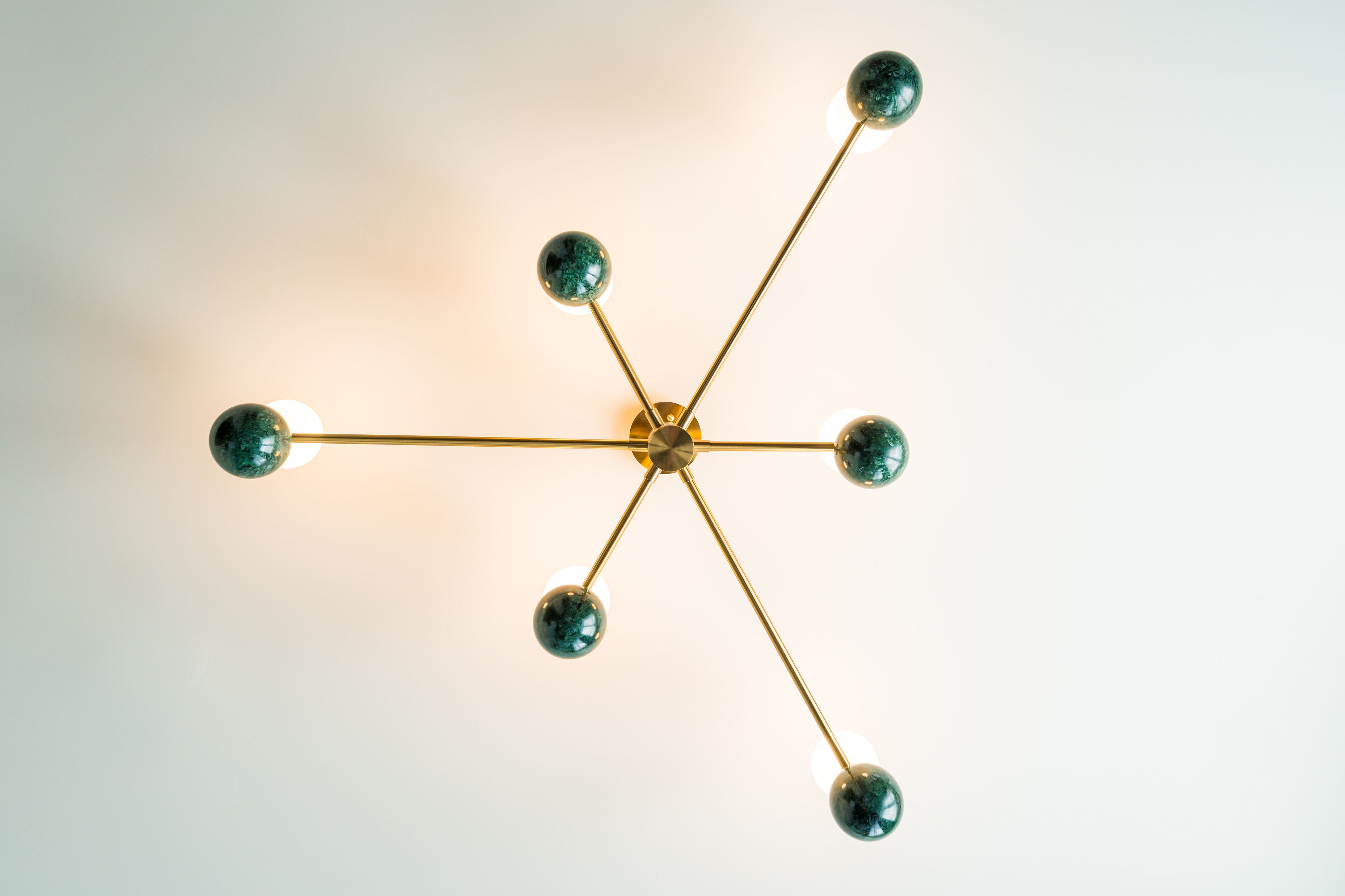 A ceiling light fixture with a central hub and multiple arms extending outward, each ending in a spherical bulb.