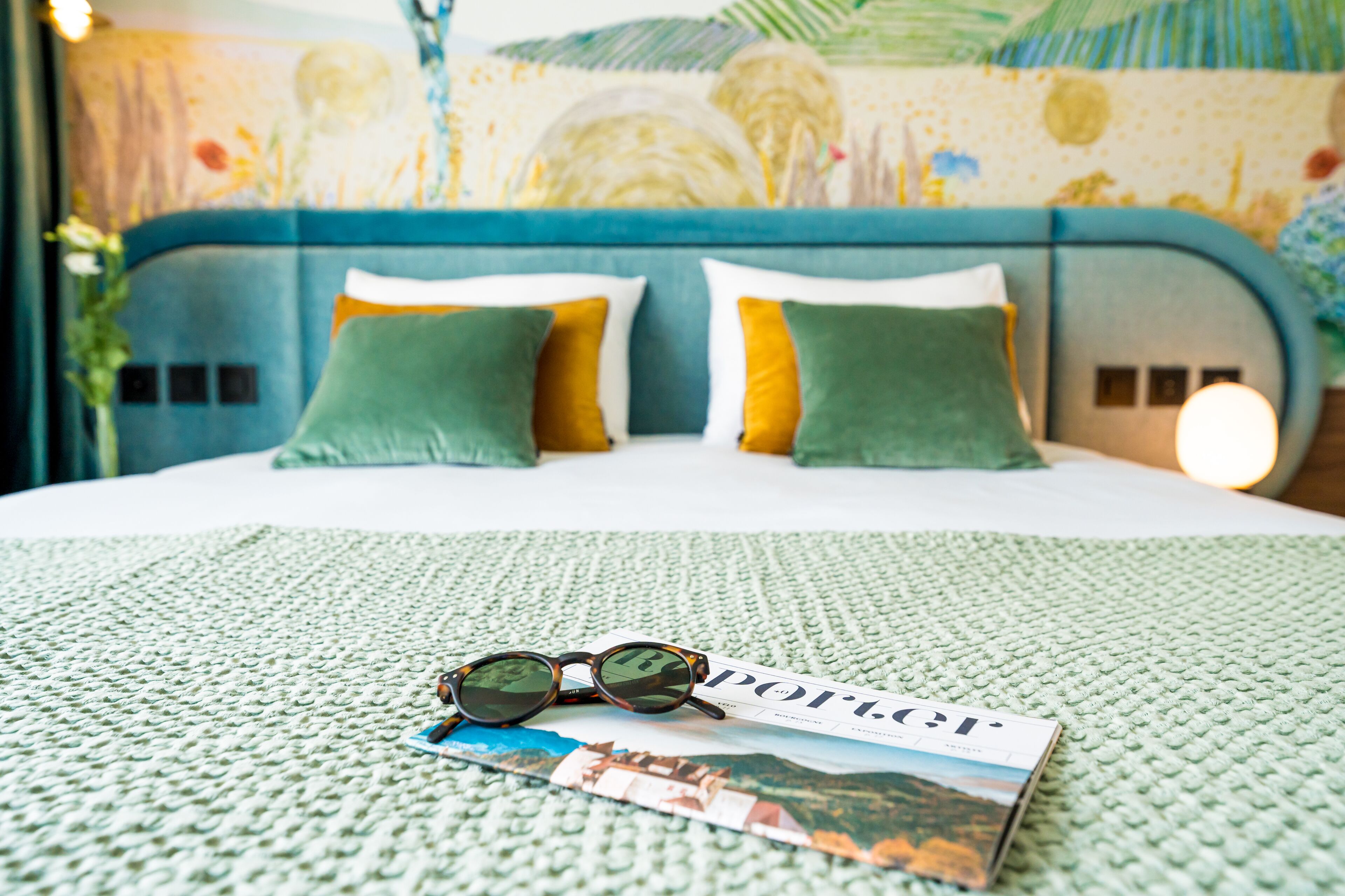Una cama con una revista, gafas de sol y una almohada.