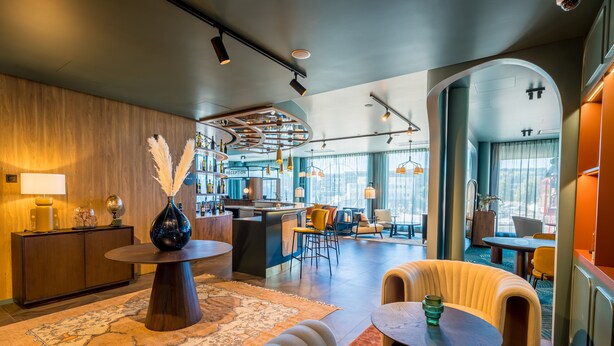 Un moderno vestíbulo de hotel con mostrador de recepción, zona de estar y bar.
