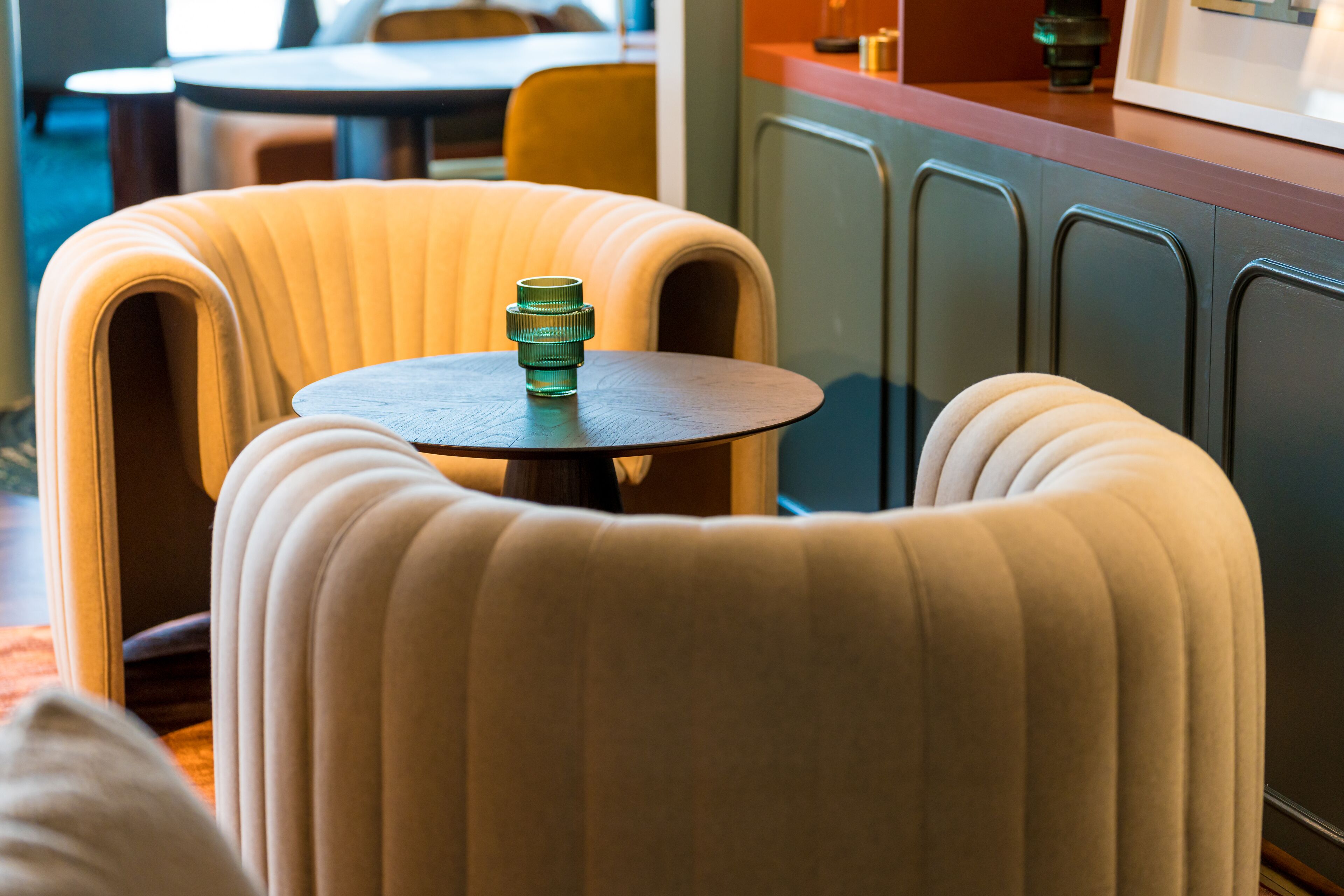 A corner seating area with a round table and a green bottle.