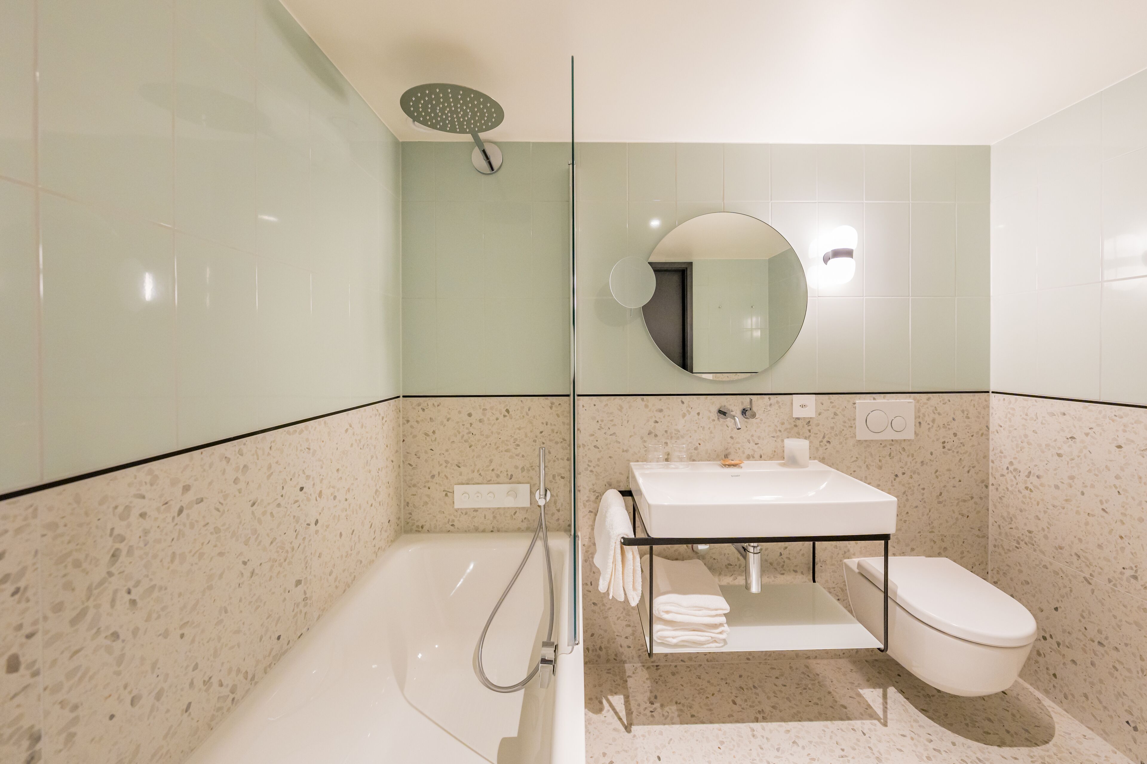 A modern bathroom with a glass-enclosed shower, a white sink, and a toilet.