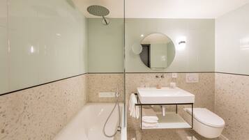 A modern bathroom with a glass-enclosed shower, a white sink, and a toilet.