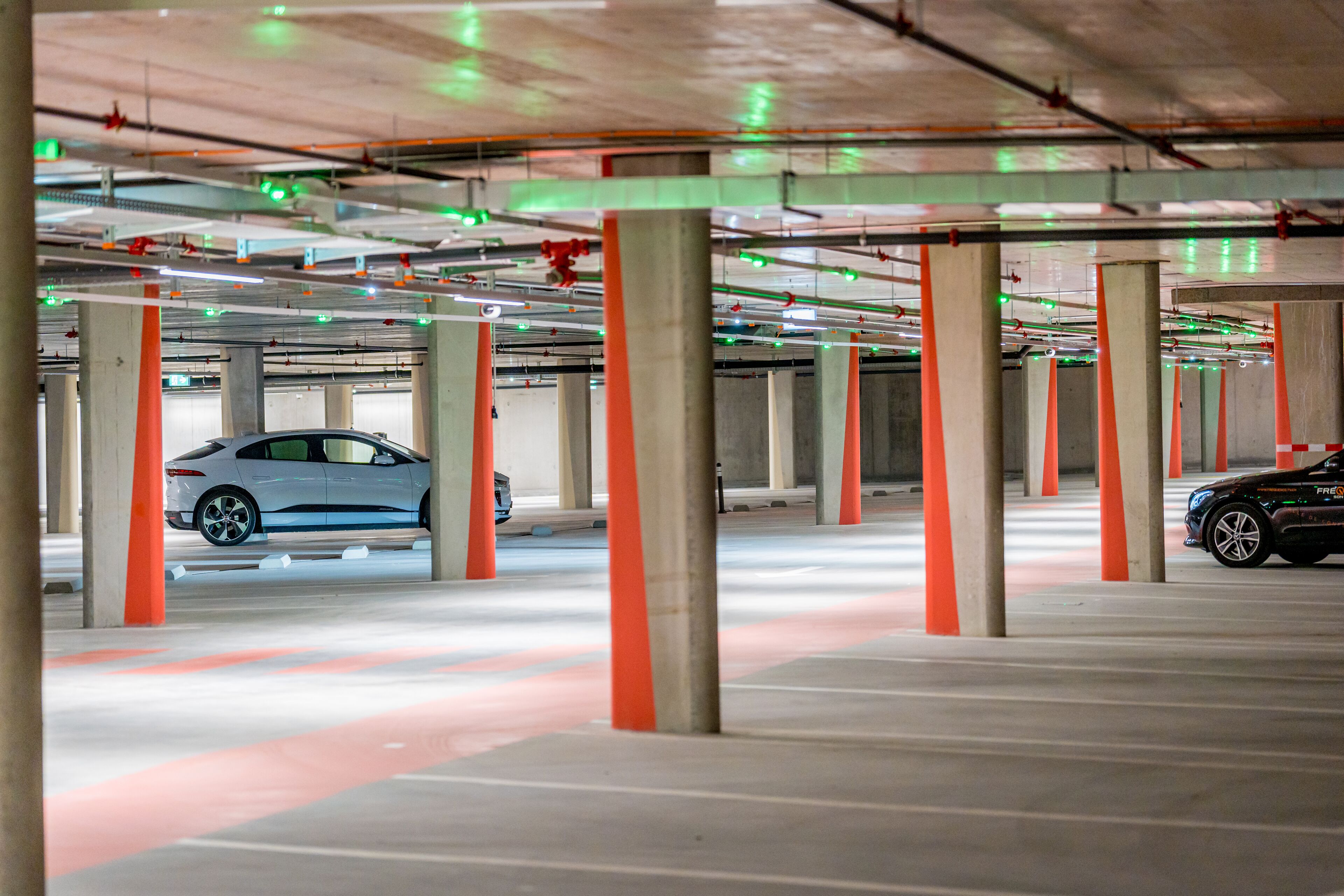 Eine mehrgeschossige Tiefgarage mit Betonpfeilern und ausgewiesenen Parkplätzen.