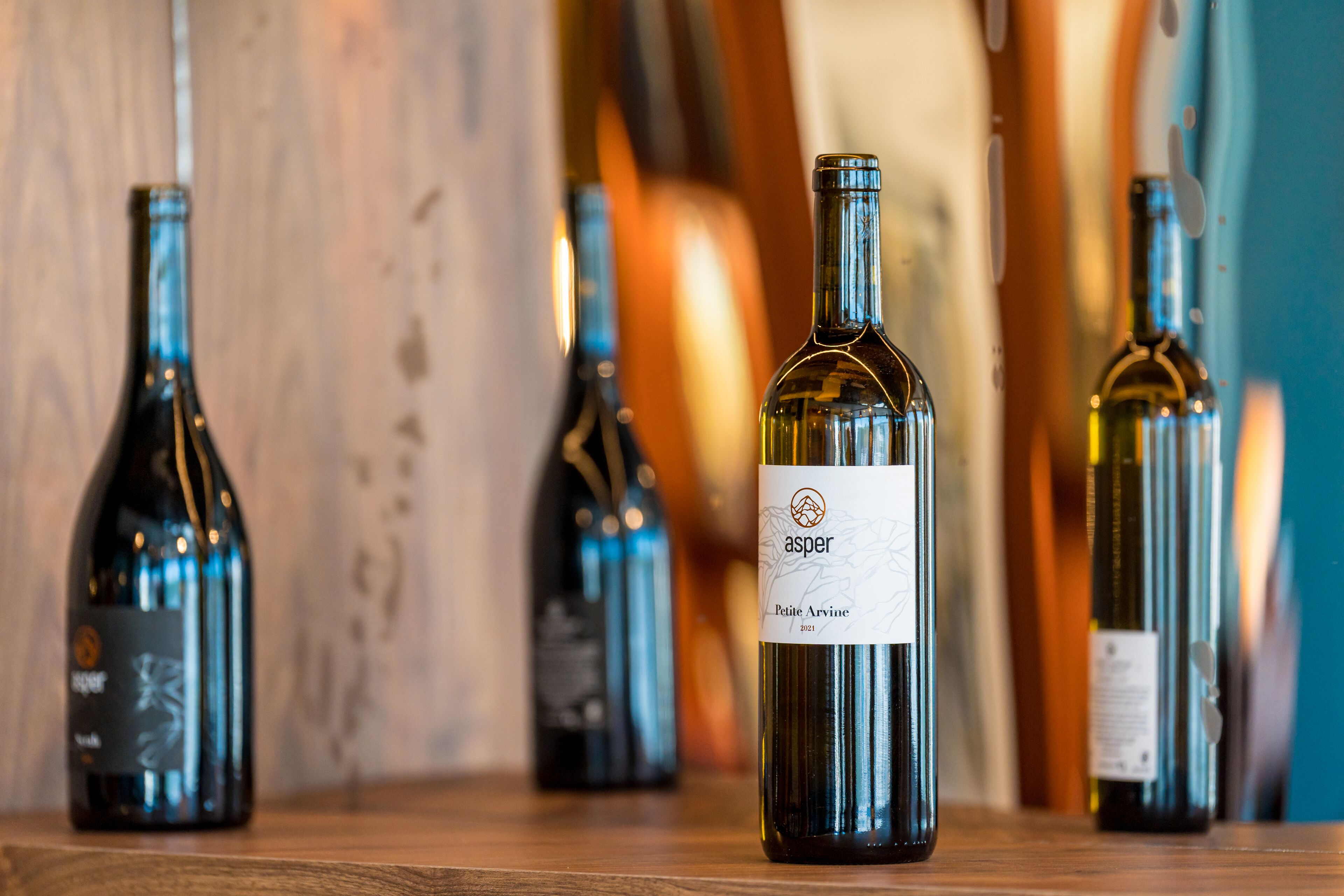 Una fila di bottiglie di vino su un piano di legno.