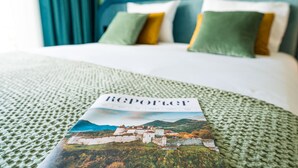 Una cama con una colcha verde con textura y una revista titulada 'Reportage' encima.