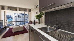 A modern kitchen with a large window, dark cabinetry, and a view of a cityscape.