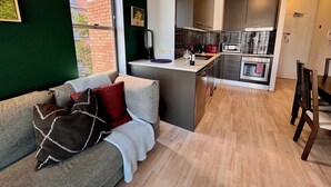 A modern kitchen with a central island, a dining area with a table and chairs, and a cozy seating area with a sofa and cushions.