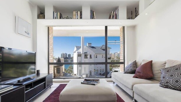 A modern living room with a large TV, a sofa, a coffee table, and a bookshelf.