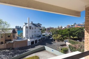 A residential building with a balcony overlooking a street and a body of water.