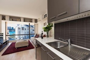 A modern kitchen with a large window, a built-in oven, and a stainless steel sink.