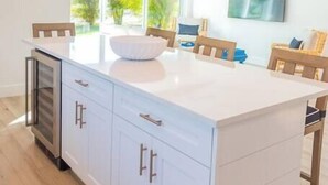 A kitchen with a large island, pendant lights, and a view of the outdoors.