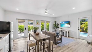 A spacious kitchen with a dining area, a television, and a view of a swimming pool.