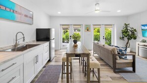 A modern kitchen with a dining area, a sofa, and a TV.