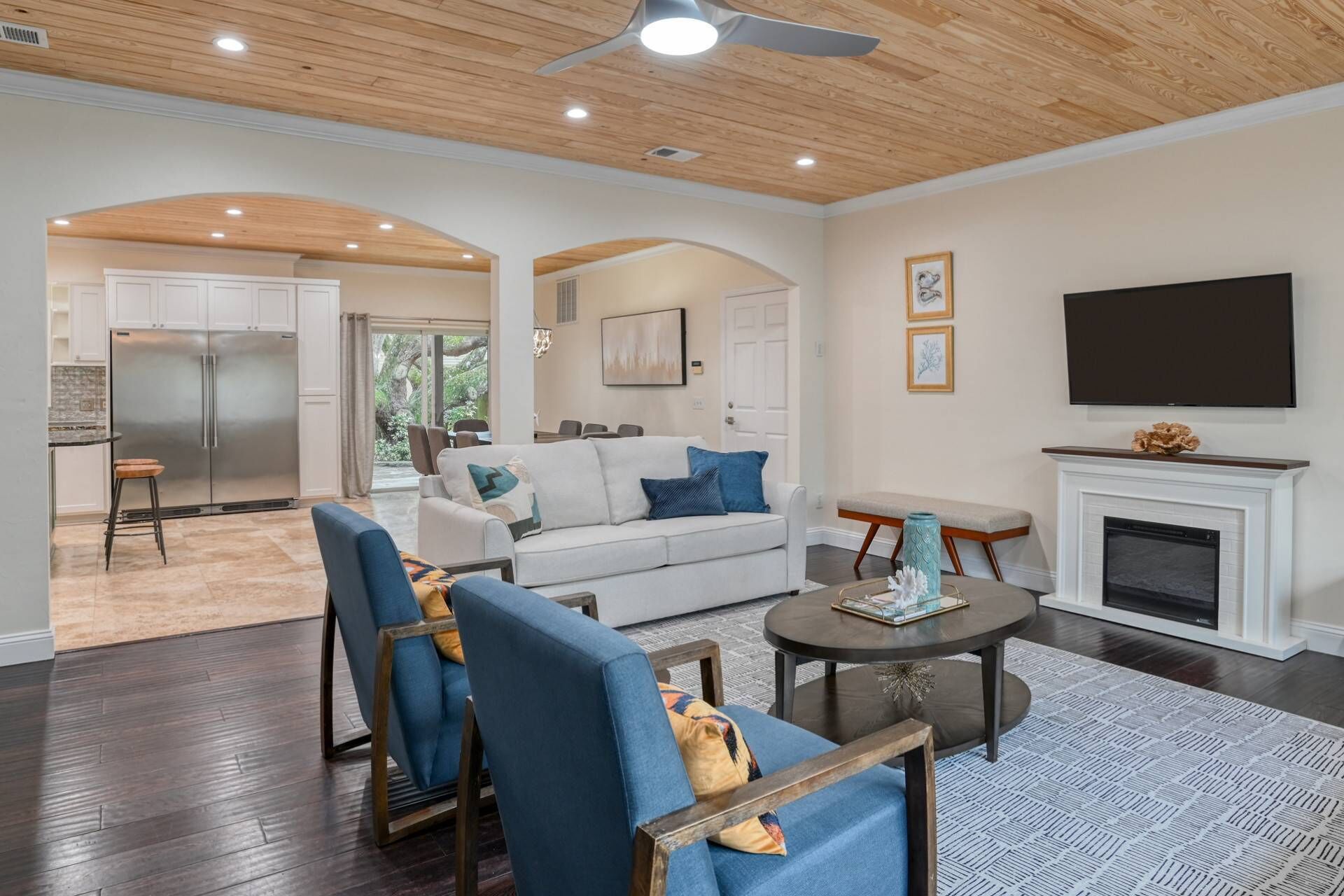 A spacious living area with a modern kitchen, a fireplace, and a large flat-screen TV.