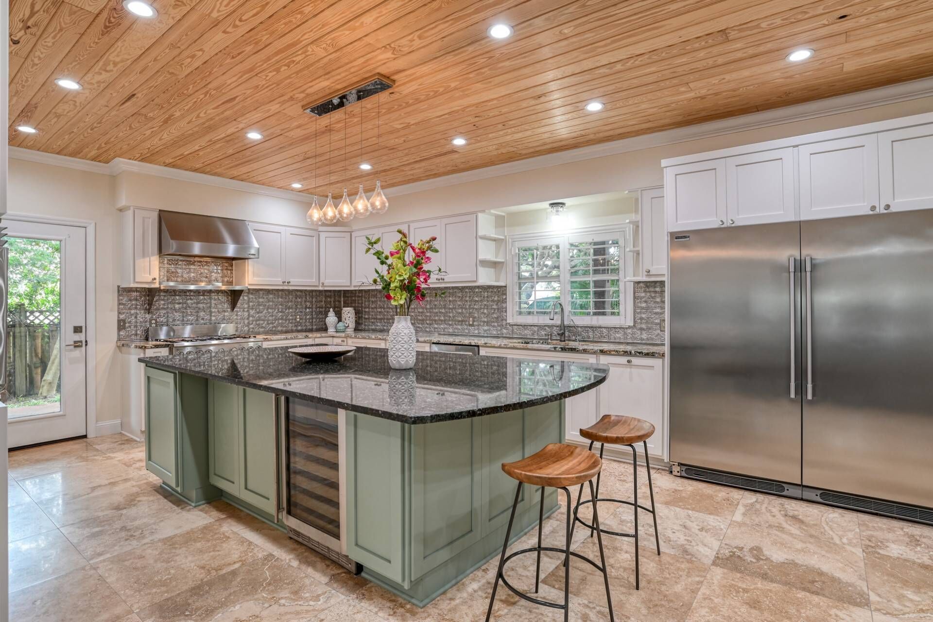 Una cocina moderna con una isla grande, electrodomésticos de acero inoxidable y techo de madera.