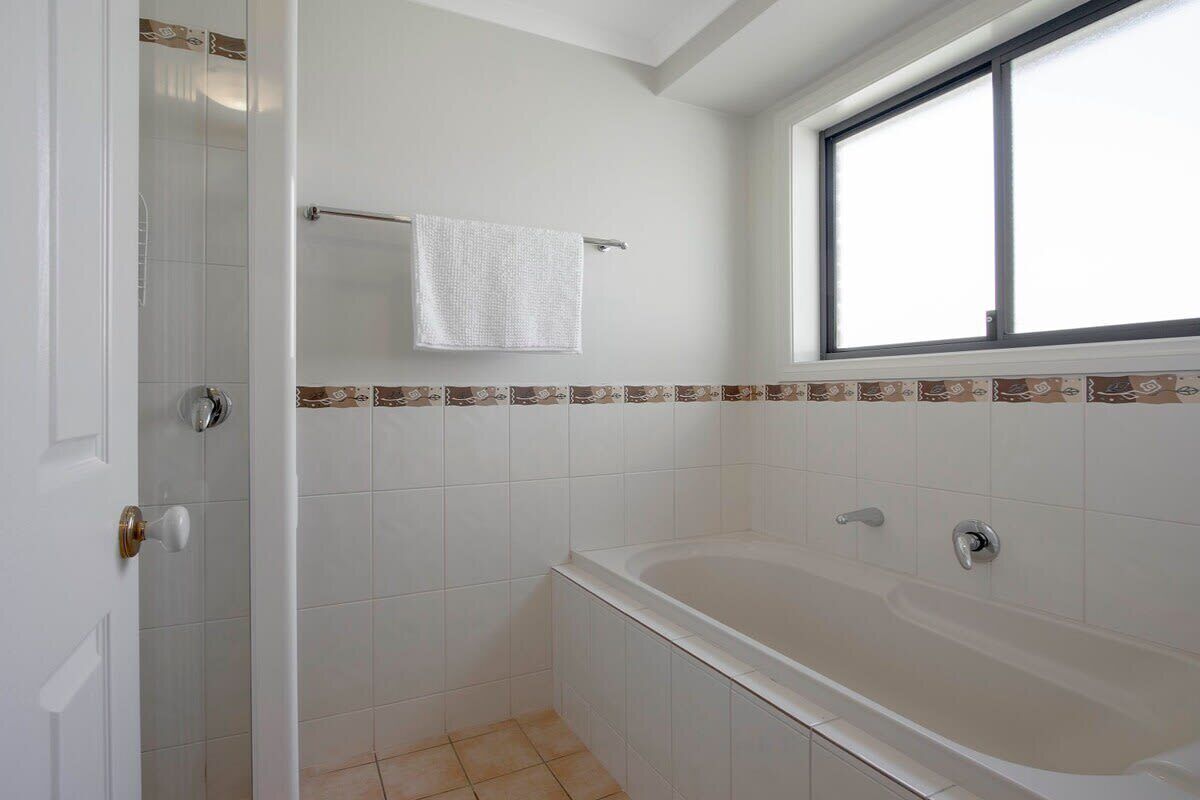 Un baño con bañera, toallero y ventana.