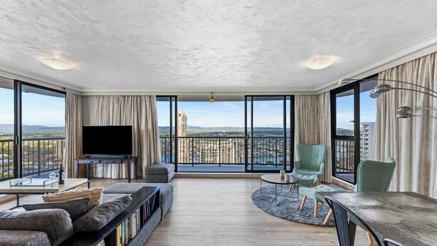 A spacious living room with a large TV, comfortable seating, and a city view. - Surfers Paradise Beachfront Pool and Views (Surfers Paradise)