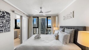 A hotel room with a bed, a ceiling fan, a view of buildings, and a door leading to a balcony. - Surfers Paradise Beachfront Pool and Views (Surfers Paradise)