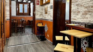 A restaurant interior with wooden furniture, a brick wall, and a sign indicating an exit. - ToledoRooms Palacios (Toledo)
