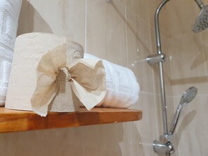 Un rollo de papel higiénico con un lazo decorativo sobre un estante de madera en un baño.