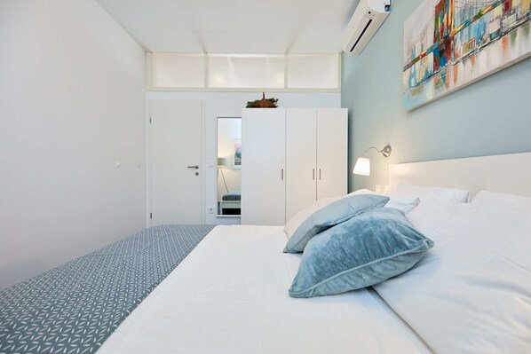 Una habitación de hotel moderna con una cama, un armario y vista al pasillo.