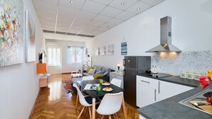 A modern kitchen with a black countertop, stainless steel appliances, and a herringbone wood floor.