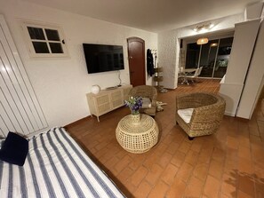 Een gezellige woonkamer met een televisie, rieten meubels en een hond die op de vloer ligt.