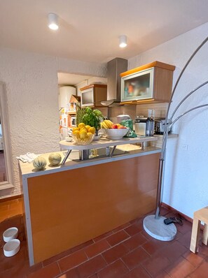 Een moderne keuken met een centraal kookeiland, een magnetron erboven en een vloerlamp.