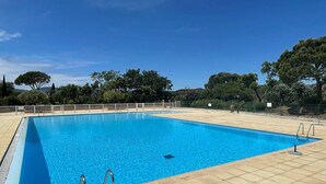 Une piscine rectangulaire à l’eau d’un bleu limpide, entourée d’une terrasse carrelée et d’une clôture blanche.