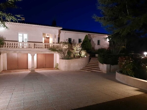 A two-story building with a tiled courtyard, a staircase, and a balcony with a railing.
