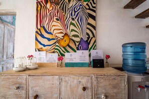 Un meuble en bois orné d’un tableau représentant un zèbre, un distributeur d’eau et plusieurs cartes de visite.