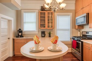 A kitchen with a central island, wooden cabinets, a stove, and a microwave. - Happy Bungalow (St. Augustine)