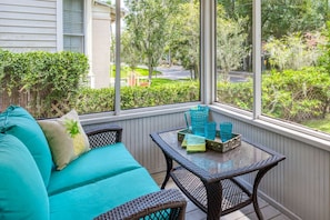 Relax in this serene space with a comfortable sofa, wicker chair, and glass table.