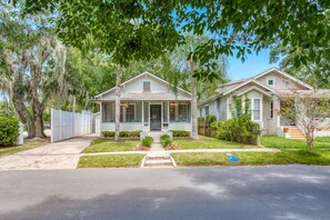A two-story residential house with a front porch, a covered entryway, and a small front yard. - Happy Bungalow (St. Augustine)