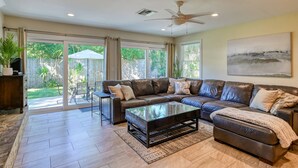 A spacious living room with a leather sectional sofa, a glass coffee table, and a ceiling fan. - La Valencia (St. Augustine)