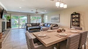 A spacious living room with a large sofa, dining table set for four, and a fireplace. - La Valencia (St. Augustine)