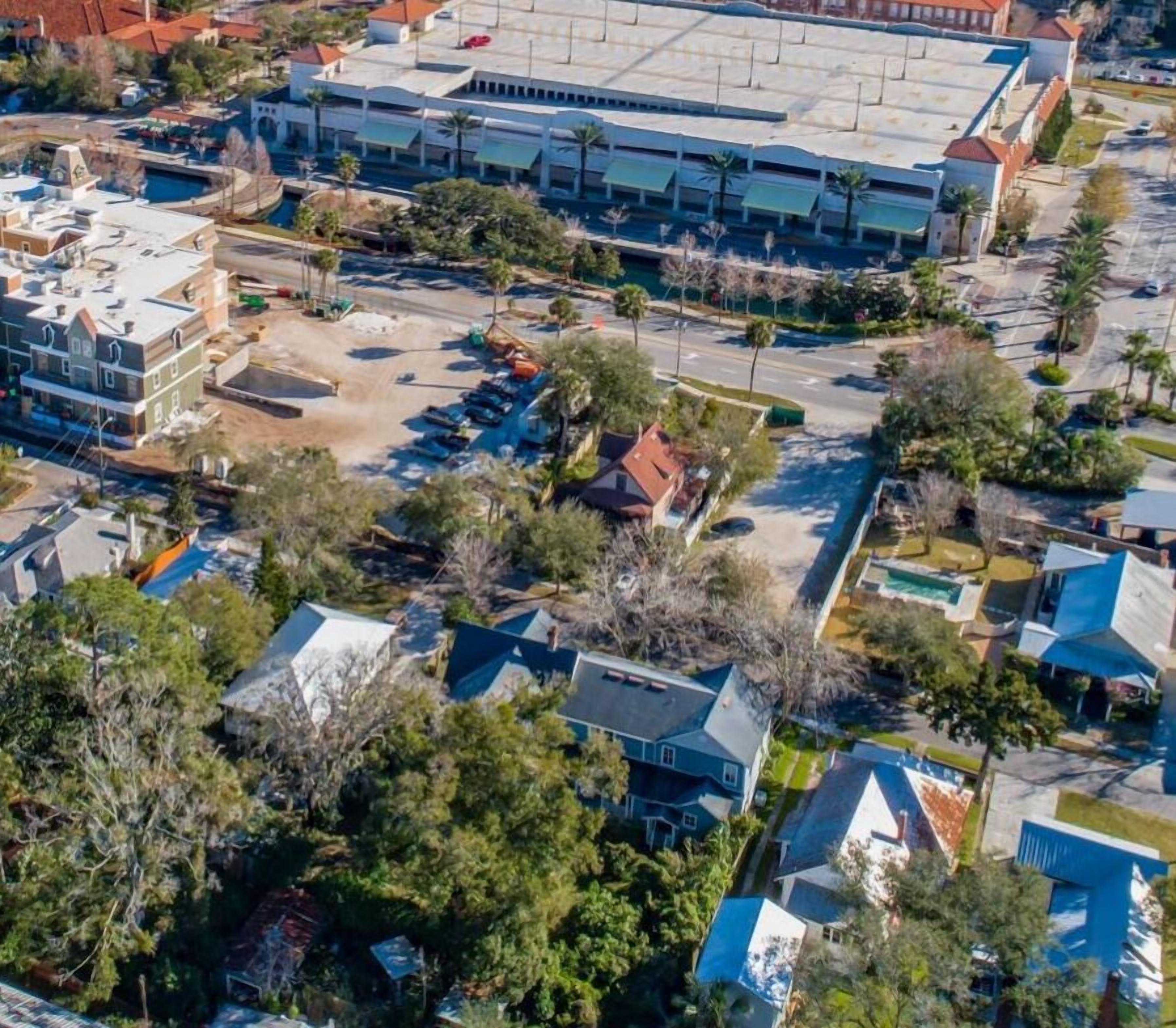Vista aérea de una zona residencial con casas, un estacionamiento y un edificio grande de techo plano.