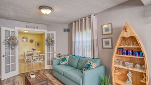 Una sala de estar con un sofá color turquesa, una estantería de madera y una puerta con la etiqueta 'JOURNEY'.