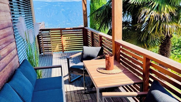 En træterrasse med en sofa, stole og et bord.