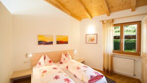 Un dormitorio con dos camas, vigas de madera en el techo, una ventana con cortinas y obras de arte en las paredes.