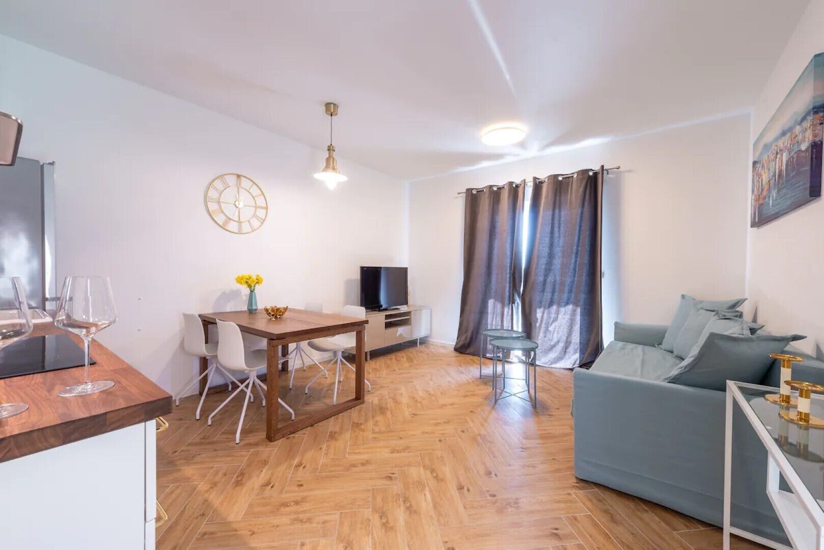 Ein modernes Wohnzimmer mit einem Holzesstisch, einem grauen Sofa und einem Fernseher.