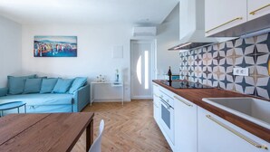 Una sala moderna con un sofá, una mesa de comedor y una cocina con salpicadero decorativo.