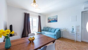 Una sala moderna con una mesa de comedor de madera, un sofá azul y un cuadro en la pared.