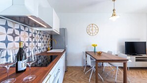 Una cocina moderna con un salpicadero geométrico, una mesa de comedor de madera y un televisor al fondo.