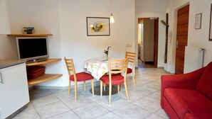 Un comedor con una mesa, sillas, un televisor y un sofá rojo.