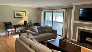 Ein Wohnzimmer mit einem beigen Sofa, einem Holztisch und einem Kamin.