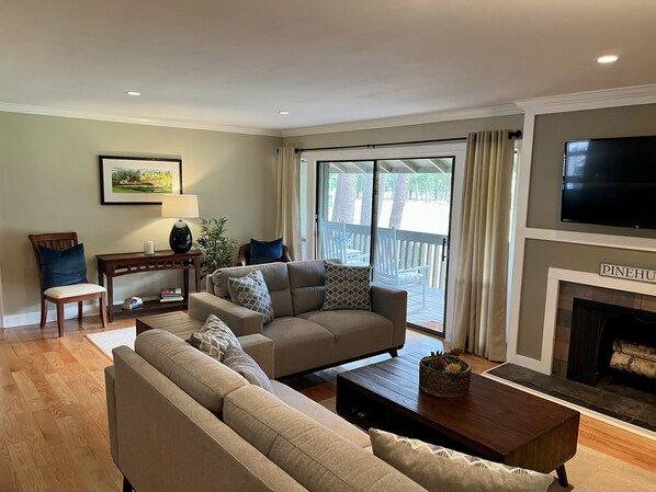 A living room with a beige sofa, a wooden coffee table, and a fireplace. - “The Cradle Cottage", 3 bed-2 bath, renovated condo a short walk to Pinehurst CC (Pinehurst)